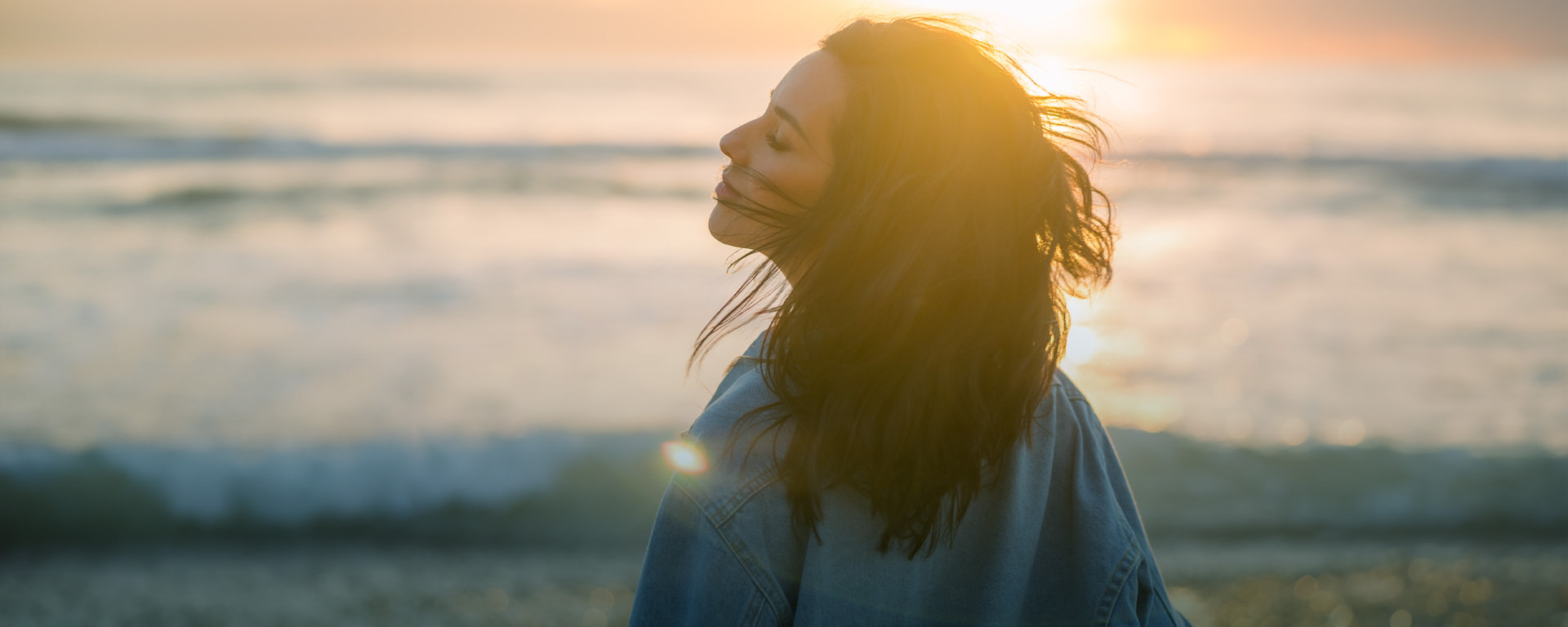 Woman breathing at the ocean at sunrise